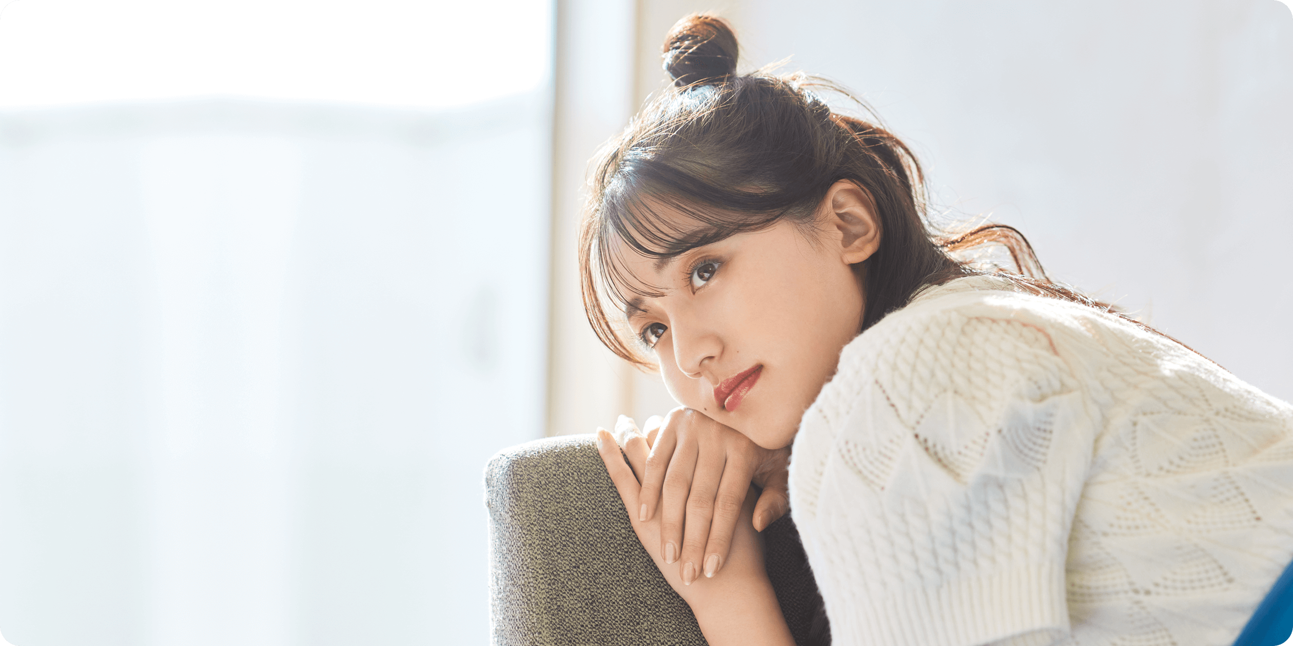 女性がソファーにもたれて、遠くを眺めている様子